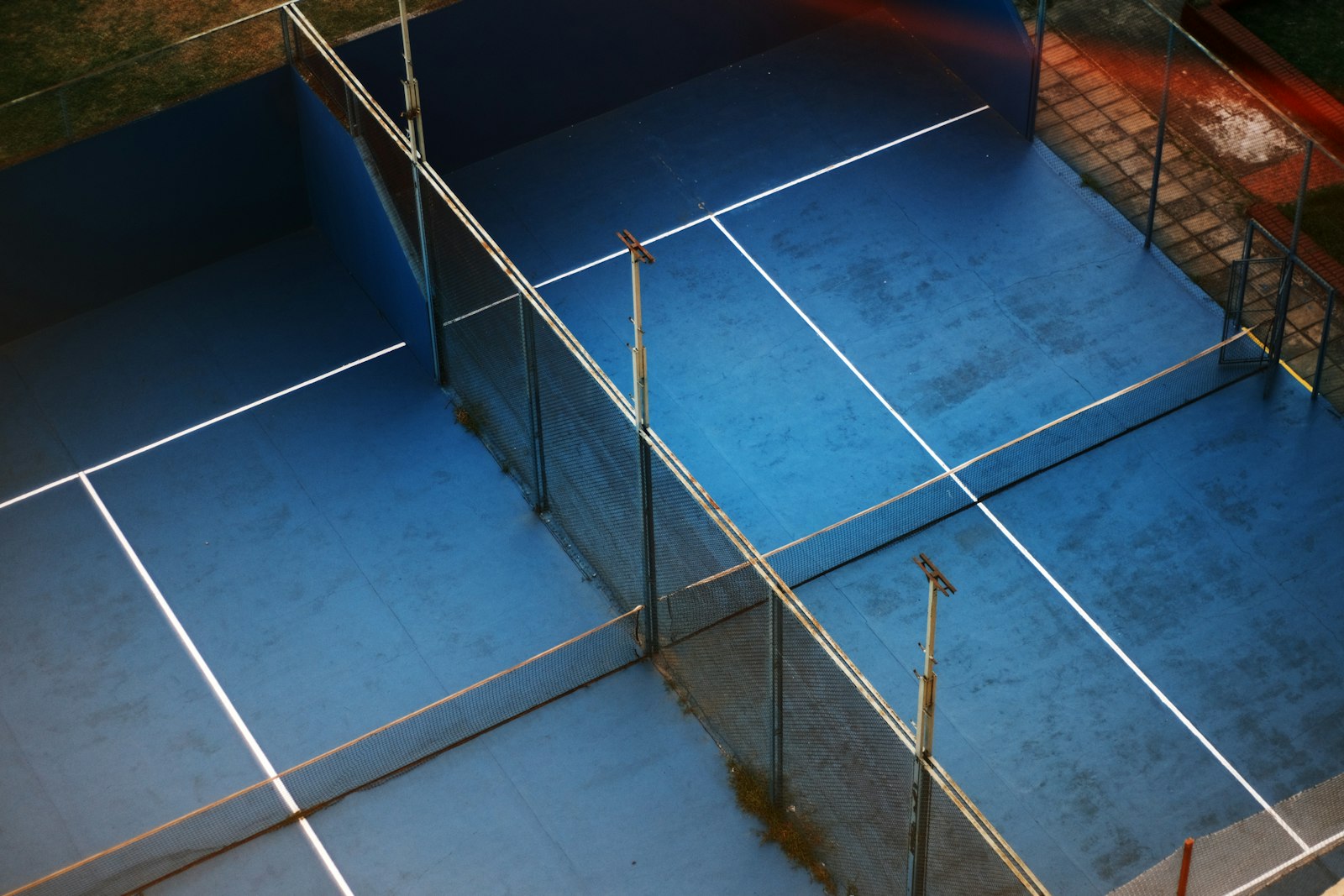 A padel court enclosed by glass walls, seen from behind the baseline