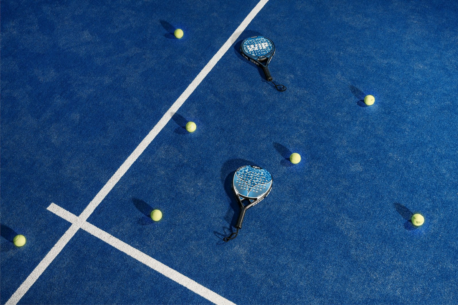 A floodlit padel court at night, seen through the glass