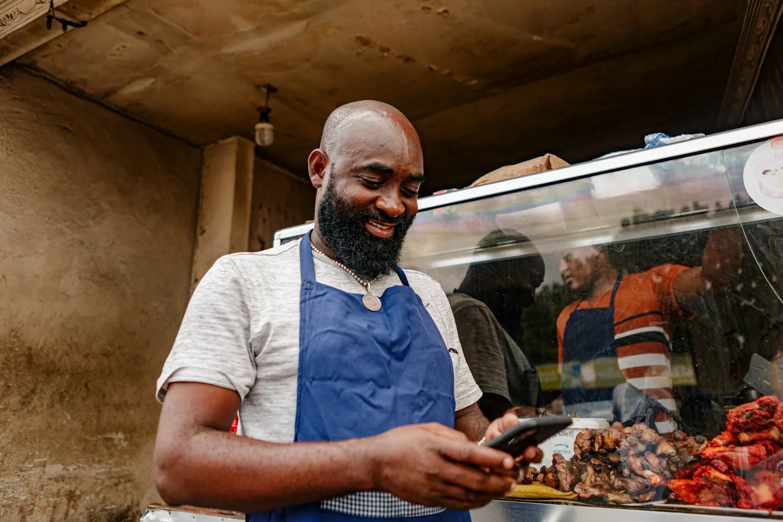 A vendor at his counter checking his phone